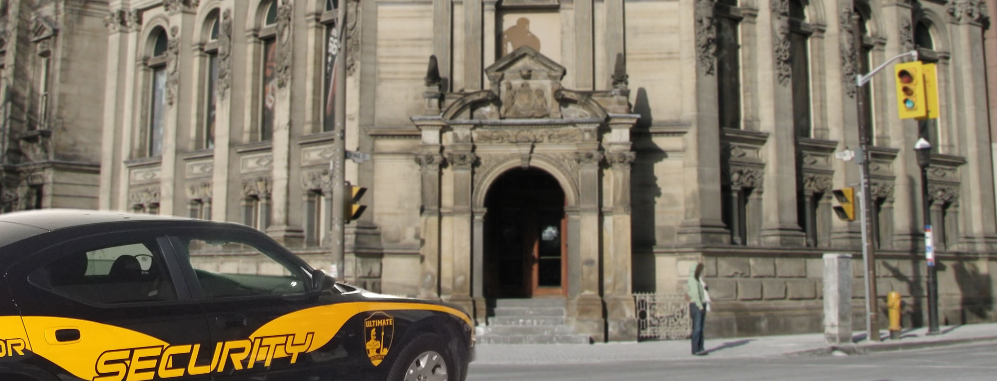 A security car, part of advanced mobile security solutions, stands vigilant in front of an ornate stone building with a large arched entrance and detailed carvings.