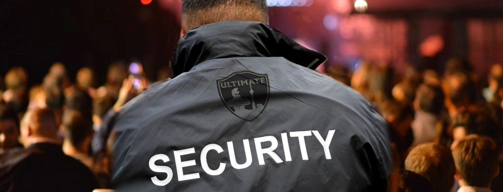A security guard wearing a jacket in front of an audience.