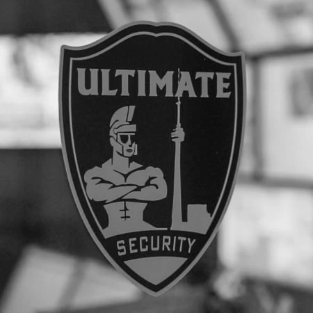 A black and white photo of the ultimate logo for security guard companies in Toronto.