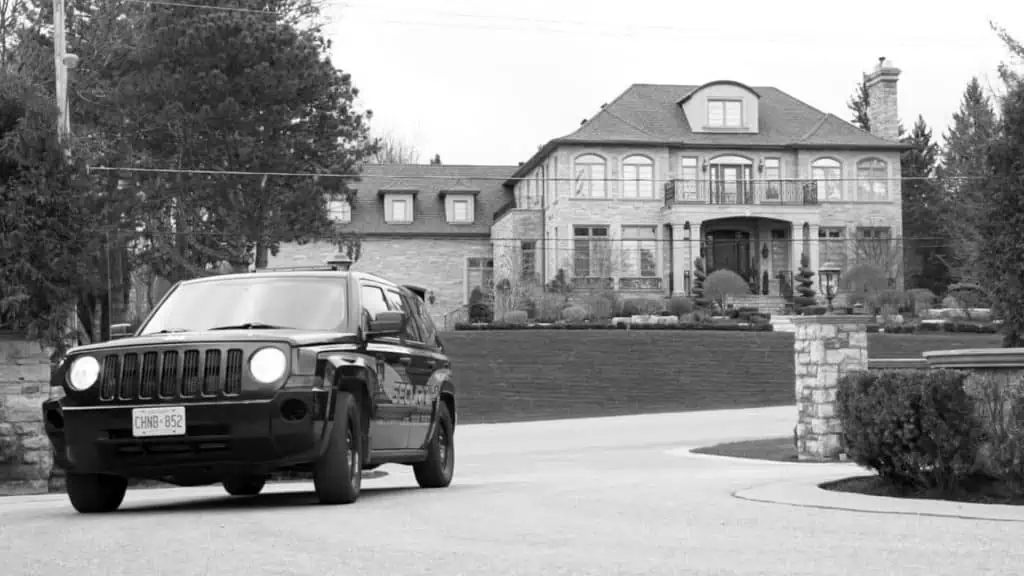 A black jeep parked in front of a large house in the Neighbourhood Watch Toronto.