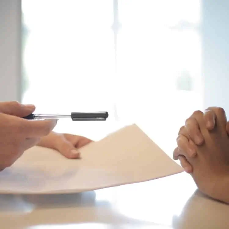 A Security Consultant is signing a document with a pen.