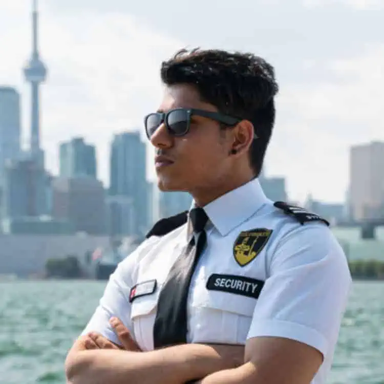A man in a police uniform standing in front of a city, representing Security Services in Toronto.