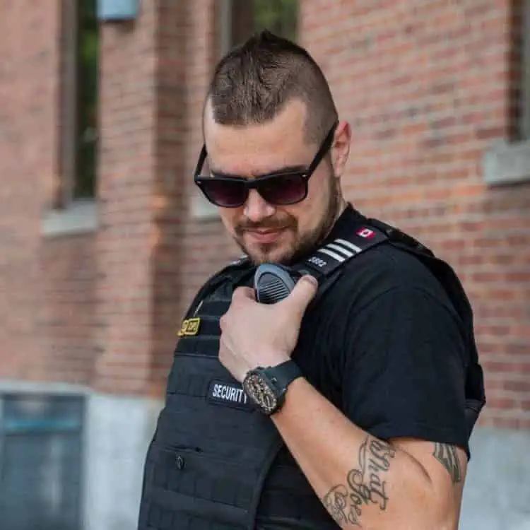 A man in a police vest holding a cell phone, suitable for hiring a security guard.