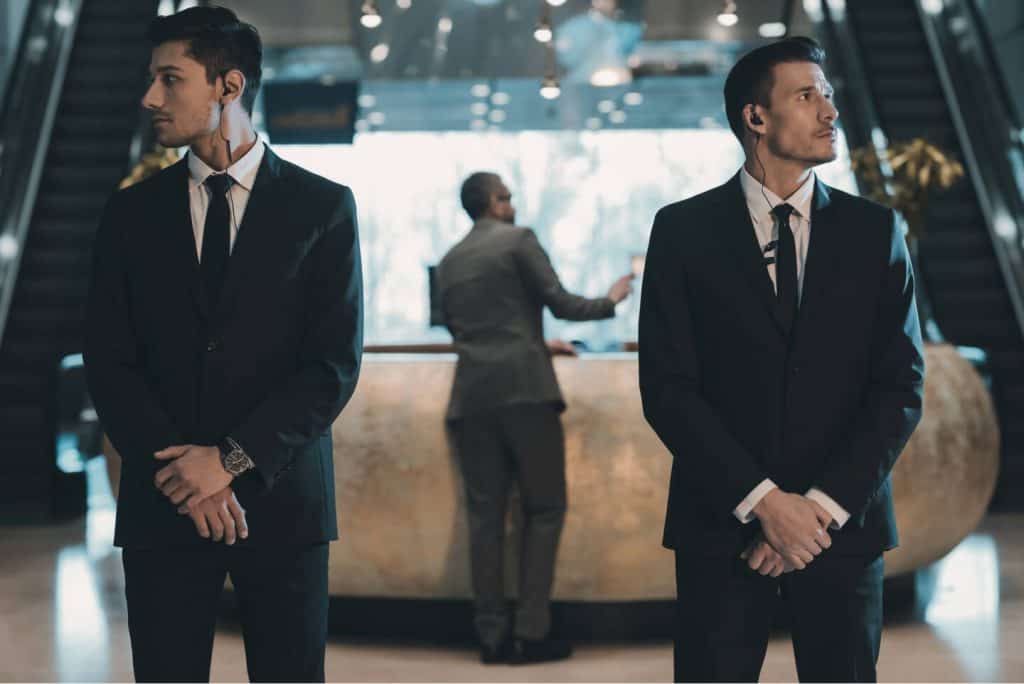 Two men, dressed in professional suits, standing in a lobby.