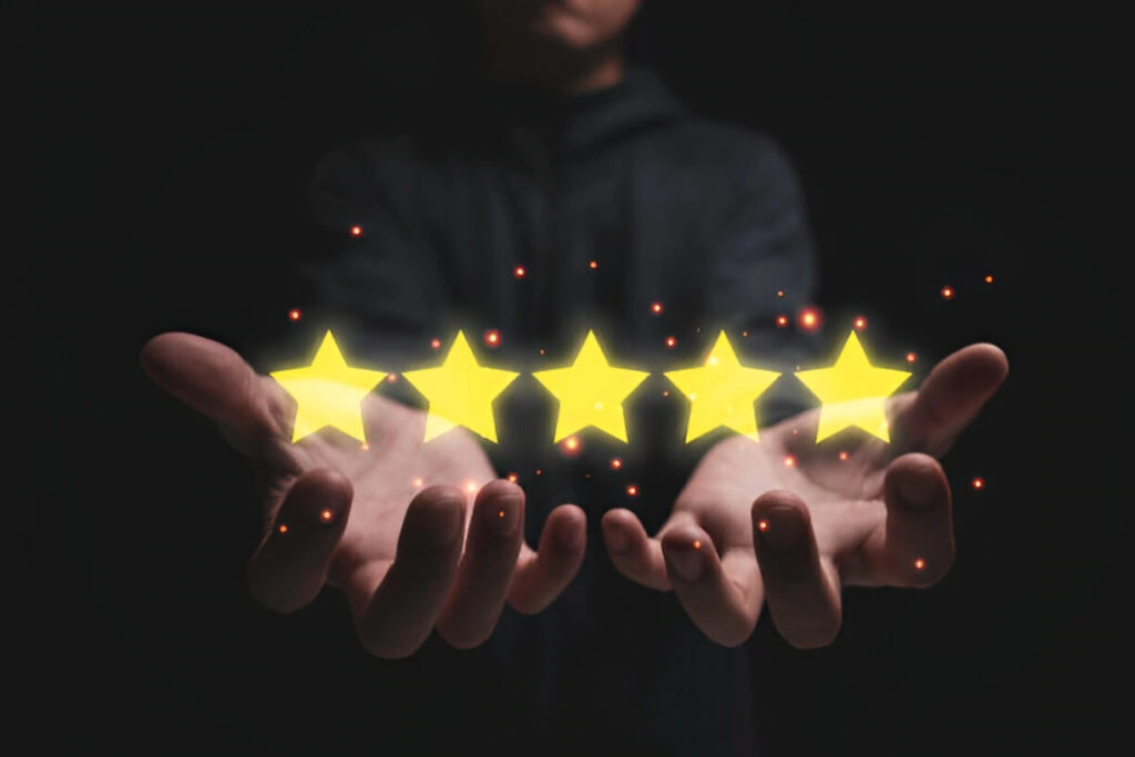 A person holds out their hands with five glowing yellow stars, symbolizing expert reputation management, appearing above them against a dark background.